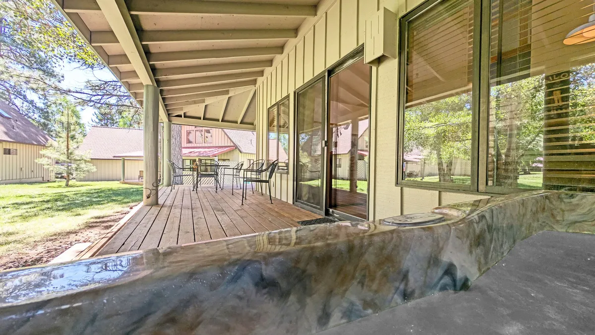 A spacious deck area is shown with comfortable outdoor seating, accessed via sliding glass doors. It’s surrounded by greenery, perfect for enjoying morning coffee, sharing meals outdoors, or winding down after a day of adventure.
