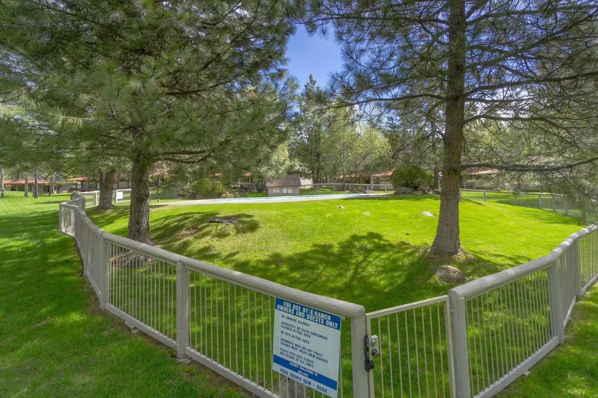 An open grassy area bordered by trees and a fenced perimeter, ideal for family activities, picnics, or outdoor games. Signage indicates a communal area, suggesting its use for group recreation and seasonal events.